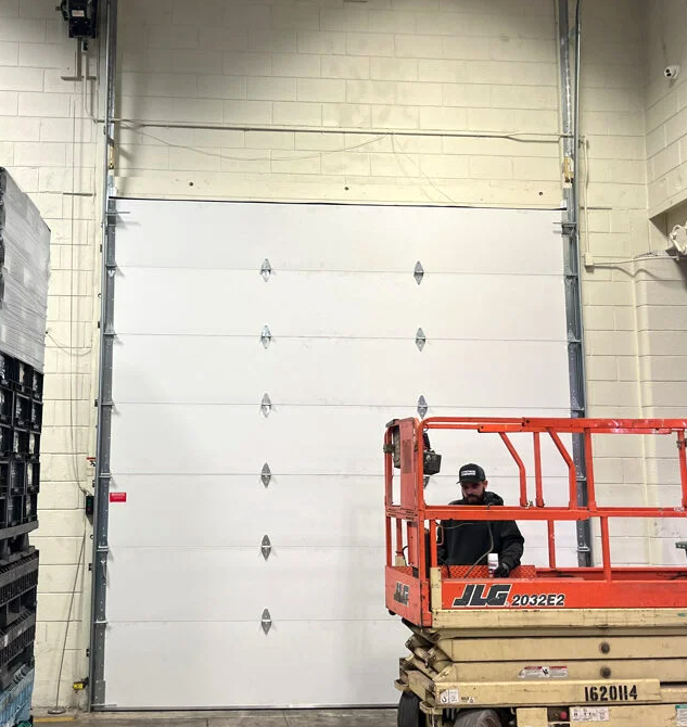 Professional technician installing a new garage door in a residential home in Bradenton, FL. Tools and equipment are visible, showcasing expert garage door installation services in the area.