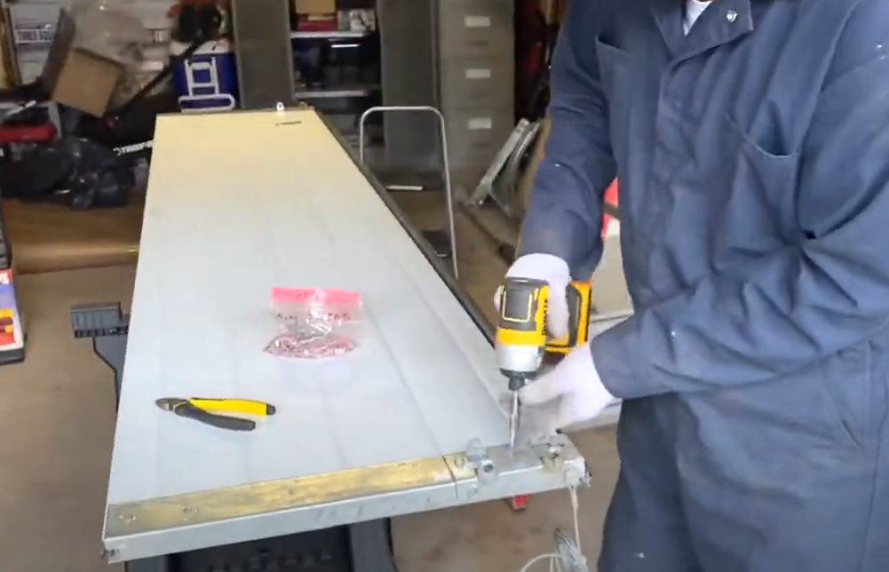 Technician repairing a damaged garage door panel in Bradenton, FL using specialized tools, showcasing professional garage door panel repair services.