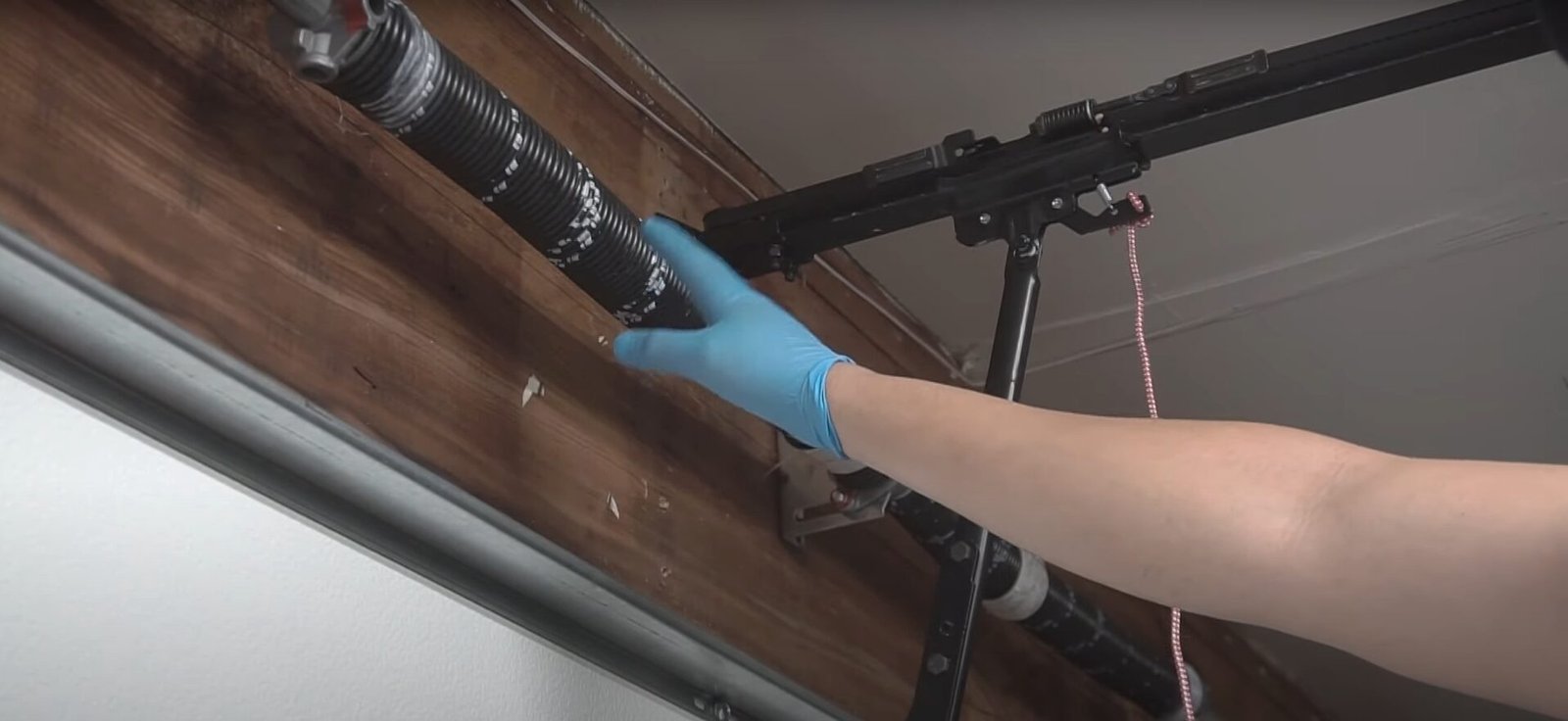 A technician from Bradenton FL Garage Door Repair inspecting a garage door spring for signs of wear and tear, ensuring safe and proper operation